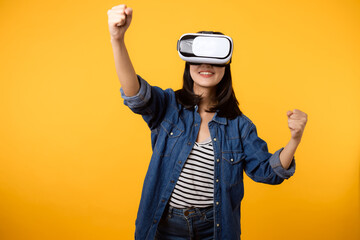 Poster - Young asian woman happy success wearing virtual reality headset game entertainment isolated on yellow background. Winner of cyber future video game concept.