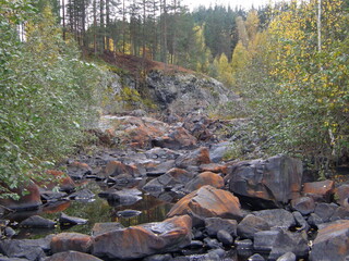 A rocky landscape with trees and rocks in the foreground. Suna River, Poor Porog Waterfall, Girvas, Republic of Karelia, Russia