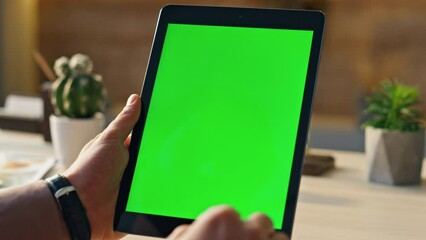 Wall Mural - hand scrolling greenscreen tablet searching information in home office close up