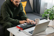 © satura_ - Man music producer or arranger using laptop and midi keyboard and other audio equipment to create music at home studio. Beat making and arranging audio content and composing song concept