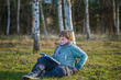 © Alina Lebed - A handsome boy in a scarf is in a spring park, sitting under a birch tree, reading a book and enjoying his dreams.