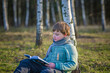 © Alina Lebed - A handsome boy in a scarf is in a spring park, sitting under a birch tree, reading a book and enjoying his dreams.