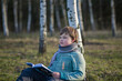© Alina Lebed - A handsome boy in a scarf is in a spring park, sitting under a birch tree, reading a book and enjoying his dreams.