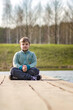 © Alina Lebed - A boy is sitting on a bridge in a green park. The path is a bridge over the lake.
