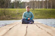 © Alina Lebed - A boy is sitting on a bridge in a green park. The path is a bridge over the lake.