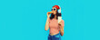 Portrait of young woman listening to music in headphones with burger fast food and cup of coffee or juice on blue background
