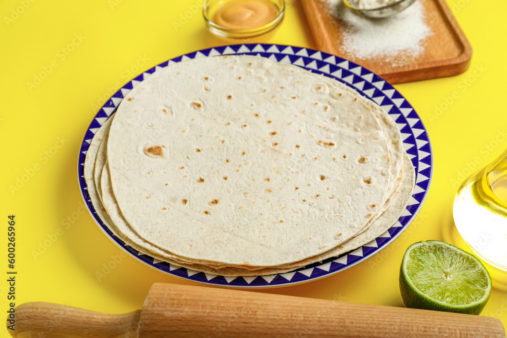 Plate with thin lavash and ingredients on yellow background