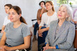 © JackF - Positive interested senior woman sitting in auditorium and listening to lecture with group of women of different ages