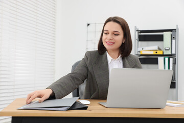 Canvas Print - Happy young intern working with laptop at table in modern office