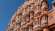 The ancient famous Palace of winds - Hawa Mahal against the blue sky. The harem building is made of red sandstone with latticed balconies decorated with white ornaments. India. Jaipur.