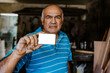 latin senior man carpenter holding blank card in his carpentry workshop in Mexico Latin America, Hispanic man portrait 