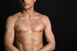 © vladorlov - Young attractive man with an athletic body on a black background.