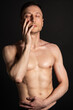 © vladorlov - Young attractive man with an athletic body on a black background.