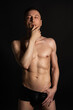 © vladorlov - Young attractive man with an athletic body on a black background.