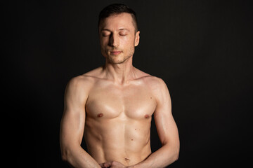 Young attractive man with an athletic body on a black background.