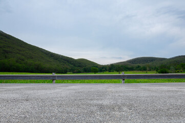 Wall Mural - Side view of empty asphalt road and cloudy mountains
