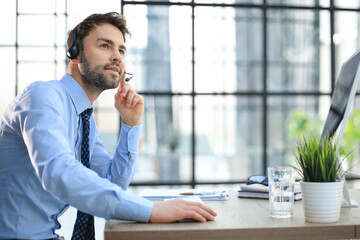 Sticker - Cheerful young support phone male operator in headset, at workplace while using computer, help service and client consulting call center concept