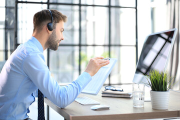 Sticker - Young man is working with papers while sitting in the office. Successful entrepreneur is studying documents with attentive and concentrated look