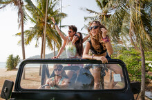 Happy Friends Enjoying Off-road Vehicle Trip At Beach