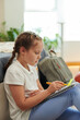 © DragonImages - Smart girl working on homework assignment when sitting on floor next to her bed