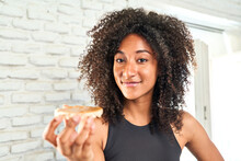 Health-conscious Young Woman In Sportswear Enjoys A Nourishing Rice Cake With Peanut Butter, Embracing A Healthy Diet.