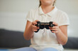 © DragonImages - Girl with controller on hands playing video game at home