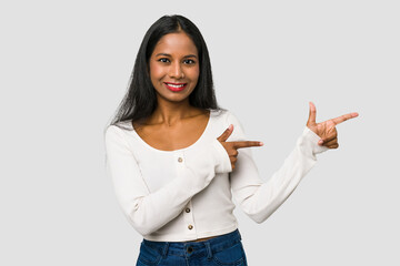 Wall Mural - Young Indian woman cut out isolated on white background excited pointing with forefingers away.