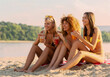 © Tijana - Three young women drinking juice on the beach, having fun