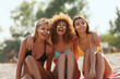 Three young women in bikinis, with sunscreen, happy smiling. 