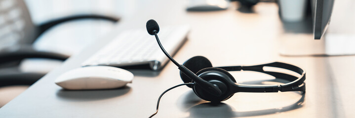 Panorama view of empty call center operator workspace, focused on headset. Representing corporate customer service support and telesales communication technology. Prodigy