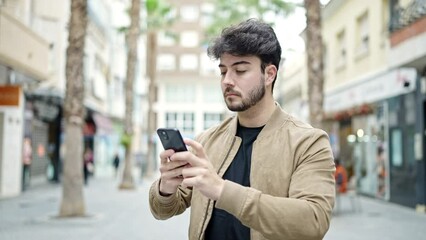 Wall Mural - Young hispanic man recording video by smartphone at street