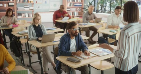 Fototapete - Diverse Mature Students Learning in Classroom, Using Laptops and Writing in Notebooks. Young Female Teacher Giving a Lecture During an Adult Education Course in School
