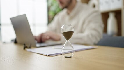 Poster - Young hispanic man business worker using laptop with hourglass at office