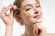 Close-up portrait of a beautiful girl applying an oil serum moisturizer to her face