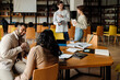 © Drobot Dean - Group of students having discussion while working on university project in library