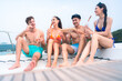 happy man in swimwear and woman in bikini having laugh fun in summer trip with friends group by eat bar-b-q grill and wine party drink, friendship vacation travel on sailboat yacht at the ocean sea