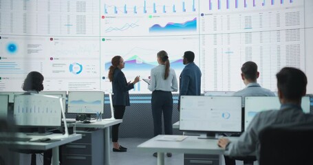 Wall Mural - Diverse Team Of Data Scientists Analyzing Information And Graphs On Big Digital Screen In Modern Monitoring Office. Multiethnic Employees Working Infront Of Desktop Computers In Consulting Firm.