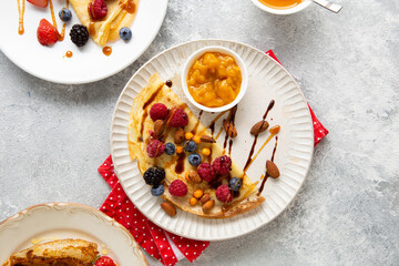 Wall Mural - Top view of crepes with berries and jam on plate breakfast food on light surface