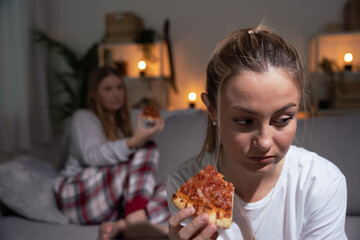 Sad woman eating pizza at night