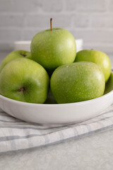 Wall Mural - Green apples in a white bowl on kitchen table