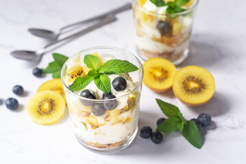 Wall Mural - blueberry and golden kiwi yogurt parfait in a glass on white background.