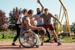 A physically challenged man in a wheelchair fearlessly engages in a spirited game of basketball with his supportive friends, breaking barriers and proving that passion and teamwork know no bounds.	