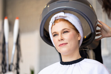 Beautiful caucasian woman red hair under hair steaming at beauty salon shop