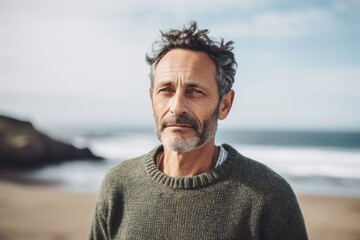 Wall Mural - Portrait of handsome mature man standing on beach and looking at camera