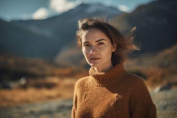 Canvas Print - Portrait of a beautiful young woman in a sweater on the background of mountains.