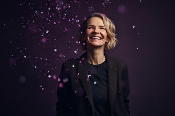 Cheerful businesswoman with flying confetti on violet background.