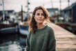 Lifestyle portrait photography of a satisfied woman in her 30s wearing a cozy sweater against a fishing village or dock background. Generative AI