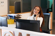 © Meeko Media - Front desk receptionist laughs on the phone, multi-ethnic woman with curly hair