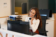 © Meeko Media - Front desk receptionist laughs on the phone, multi-ethnic woman with curly hair