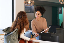 Young Woman Checks In At Front Desk, Reception, Hotel, College Library Admission